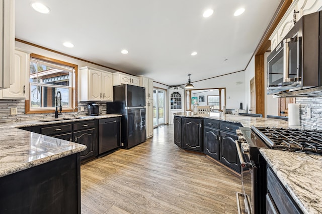 kitchen featuring light stone countertops, appliances with stainless steel finishes, white cabinets, and sink