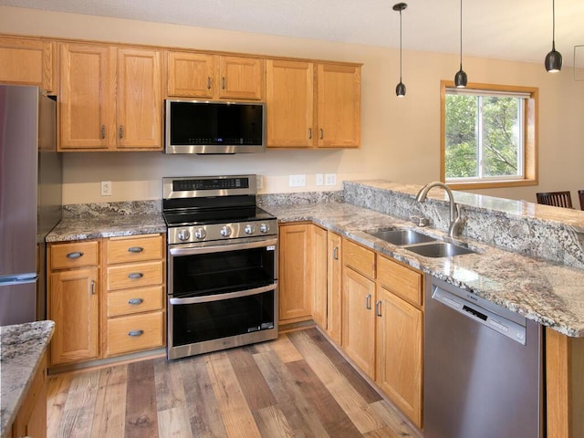 3781 Willowwood St SW, Prior Lake, MN 55372 - kitchen featuring appliances with stainless steel finishes, a peninsula, light wood-style floors, light stone counters, and pendant lighting