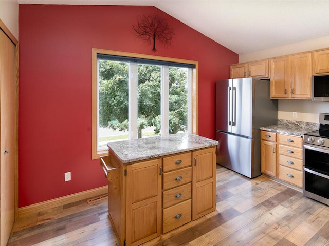3781 Willowwood St SW, Prior Lake, MN 55372 - kitchen featuring appliances with stainless steel finishes, light wood finished floors, vaulted ceiling, light stone counters, and a kitchen island