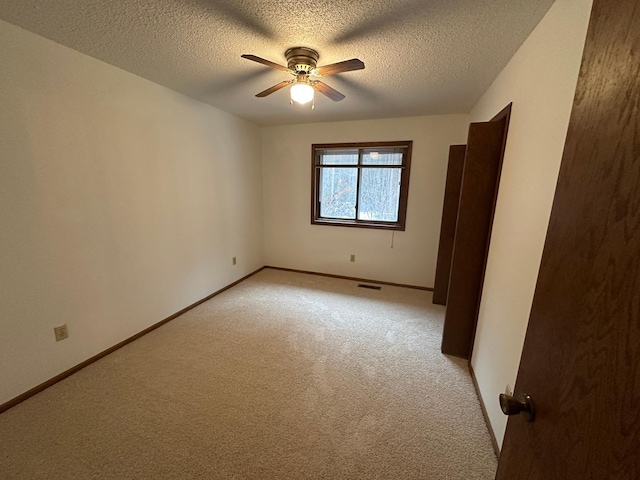 carpeted empty room with a textured ceiling and ceiling fan