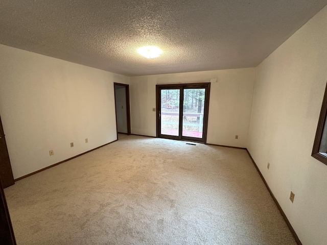 carpeted empty room featuring a textured ceiling