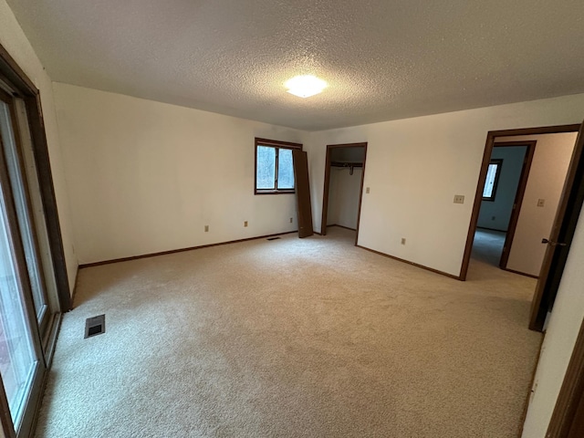 unfurnished bedroom with light colored carpet and a textured ceiling