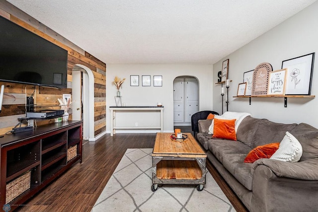 living room featuring wood walls, dark hardwood / wood-style flooring, and a textured ceiling