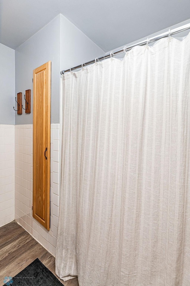 bathroom featuring wood-type flooring and tile walls