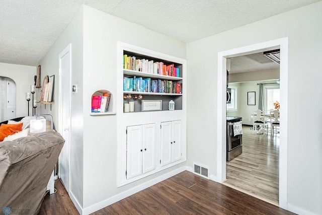 hall featuring dark hardwood / wood-style flooring, built in features, and a textured ceiling