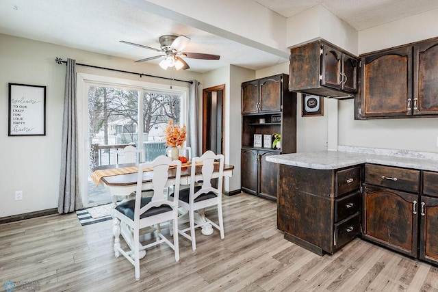 kitchen featuring kitchen peninsula, dark brown cabinets, light hardwood / wood-style flooring, and ceiling fan