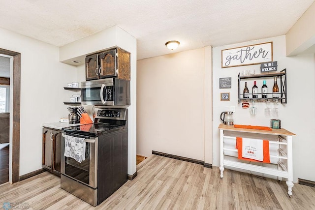 kitchen featuring dark brown cabinets, a textured ceiling, appliances with stainless steel finishes, and light hardwood / wood-style flooring