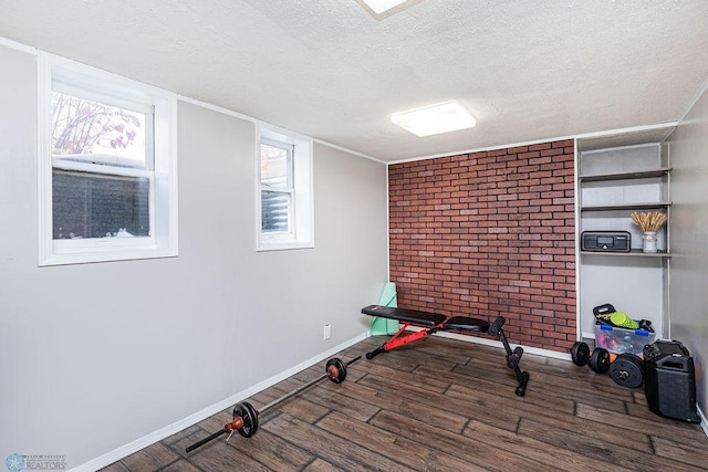 exercise room featuring dark hardwood / wood-style flooring, brick wall, and a textured ceiling