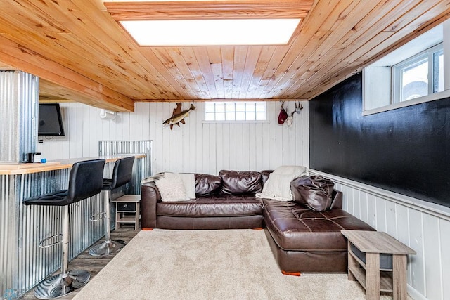 living room featuring a healthy amount of sunlight, wooden ceiling, wooden walls, and bar area