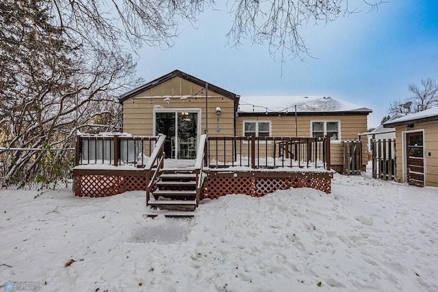 snow covered back of property featuring a wooden deck