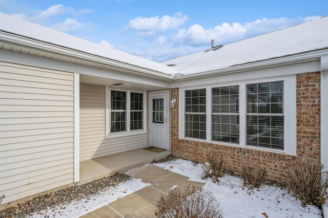 snow covered property entrance featuring a patio