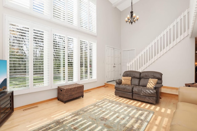 living room featuring hardwood / wood-style flooring, a notable chandelier, and high vaulted ceiling