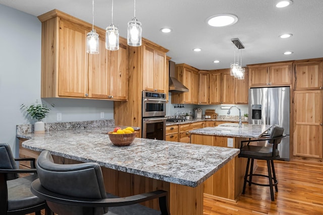 kitchen with decorative light fixtures, appliances with stainless steel finishes, a kitchen breakfast bar, light stone countertops, and a kitchen island with sink