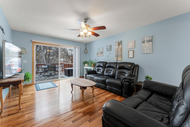 living room with ceiling fan, light hardwood / wood-style flooring, and a textured ceiling