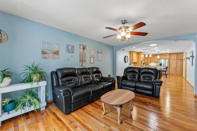 living room featuring ceiling fan, a textured ceiling, and light hardwood / wood-style floors