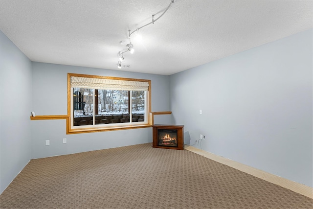 empty room featuring rail lighting, carpet floors, and a textured ceiling