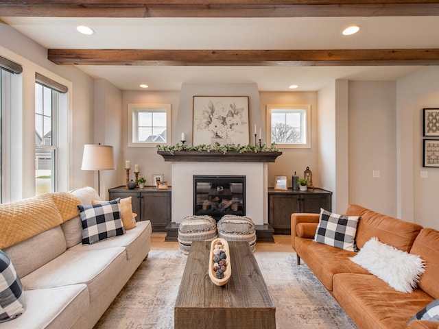 living room featuring beamed ceiling, a wealth of natural light, and light hardwood / wood-style flooring