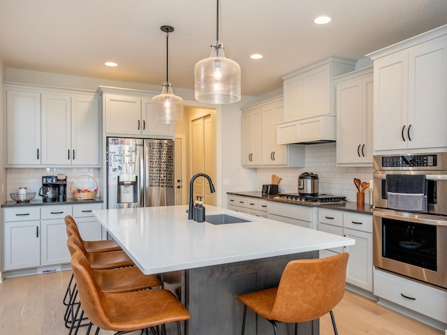 kitchen featuring appliances with stainless steel finishes, backsplash, light hardwood / wood-style flooring, and sink