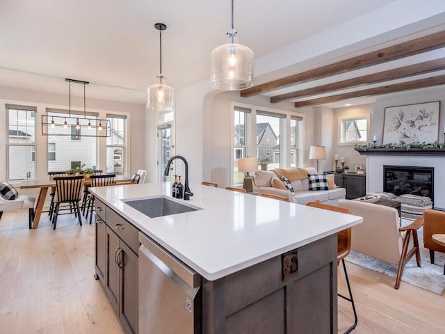 kitchen featuring dishwasher, light hardwood / wood-style floors, sink, and decorative light fixtures