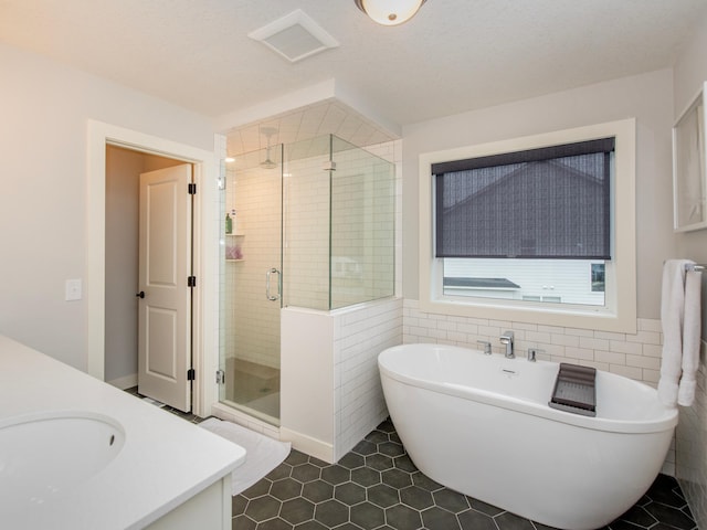 bathroom featuring tile patterned flooring, vanity, separate shower and tub, and tile walls