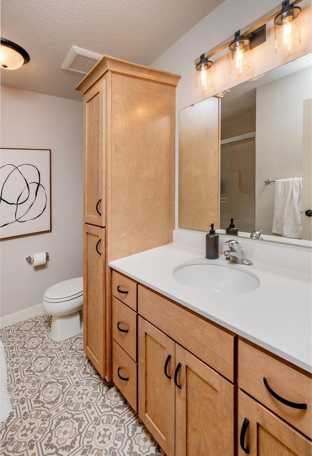 bathroom with tile patterned flooring, a textured ceiling, an enclosed shower, toilet, and vanity