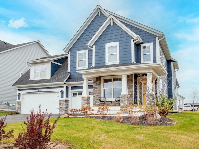 craftsman inspired home with covered porch, a garage, and a front yard