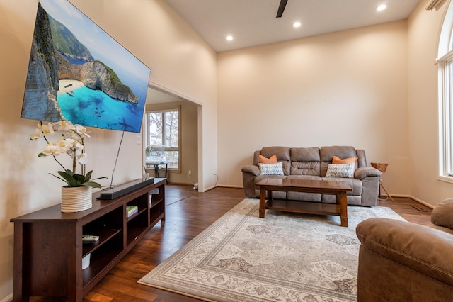 living room with ceiling fan, a high ceiling, and dark hardwood / wood-style floors