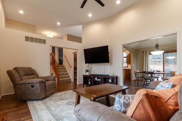 living room with hardwood / wood-style floors, ceiling fan, and a high ceiling