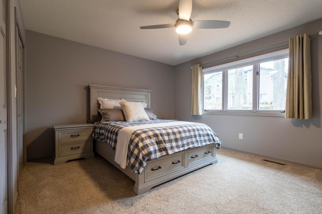 carpeted bedroom with ceiling fan and a textured ceiling