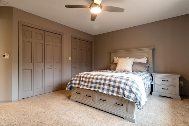 carpeted bedroom with ceiling fan and multiple closets