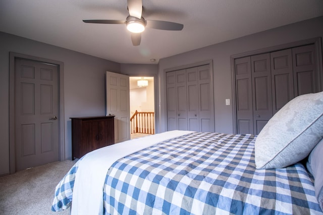 bedroom with carpet flooring, two closets, and ceiling fan