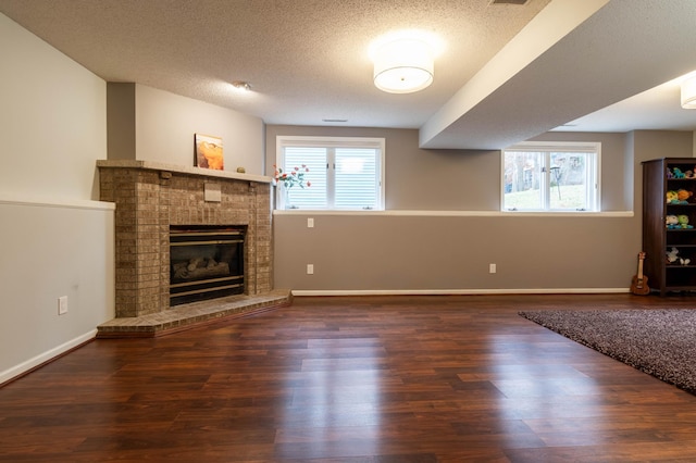 unfurnished living room with dark hardwood / wood-style flooring, a textured ceiling, and a wealth of natural light