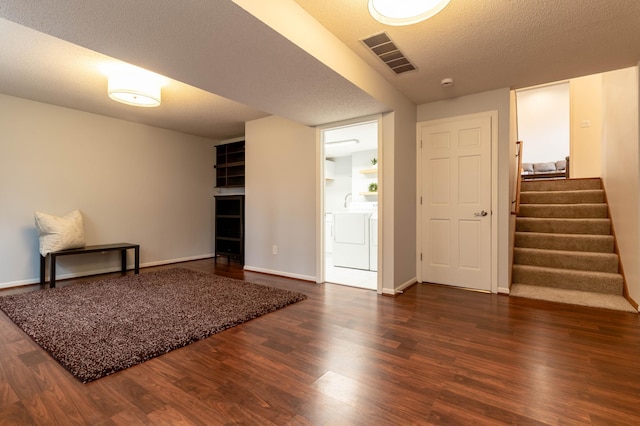 interior space featuring a textured ceiling, dark wood-type flooring, and washing machine and clothes dryer