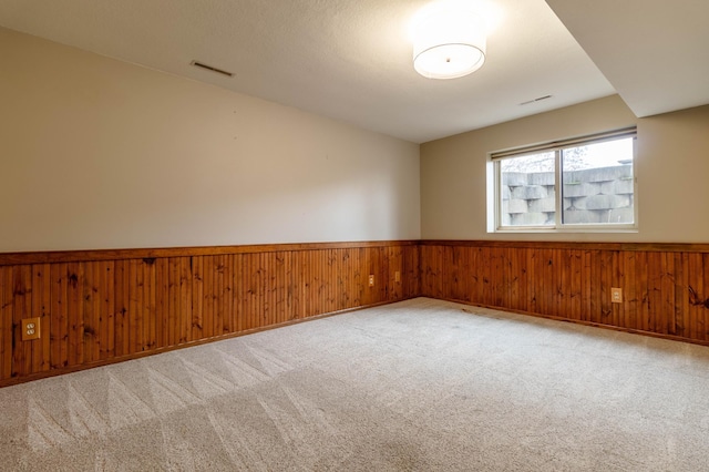 spare room with carpet and wooden walls