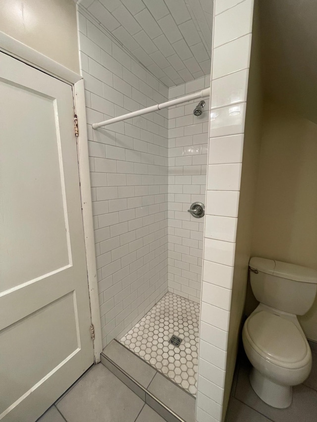 bathroom featuring a tile shower, tile patterned flooring, and toilet