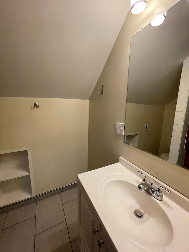 bathroom with tile patterned flooring, vanity, toilet, and lofted ceiling