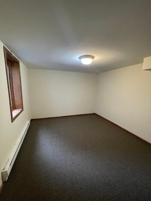 spare room featuring dark carpet and baseboard heating