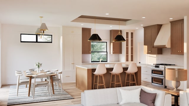 kitchen with pendant lighting, backsplash, premium range hood, range with two ovens, and light wood-type flooring