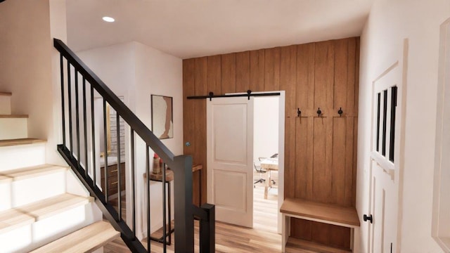 stairs featuring hardwood / wood-style floors, a barn door, and wooden walls