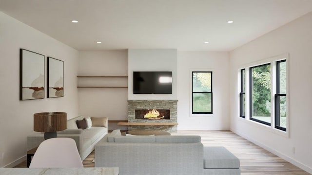 living room featuring a stone fireplace and light hardwood / wood-style flooring