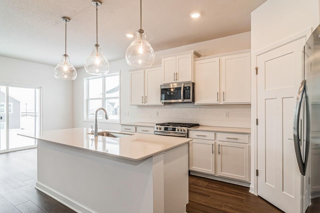 kitchen with white cabinets, pendant lighting, stainless steel appliances, and sink