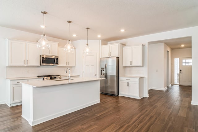 kitchen featuring white cabinetry, sink, hanging light fixtures, an island with sink, and appliances with stainless steel finishes