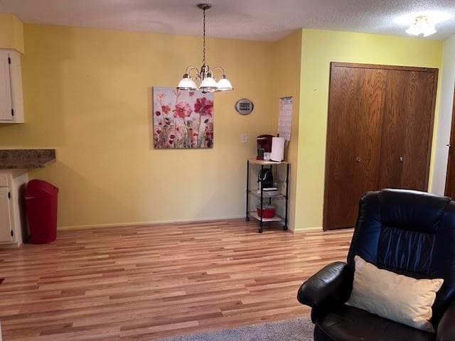 living area with a textured ceiling, a notable chandelier, and light wood-type flooring