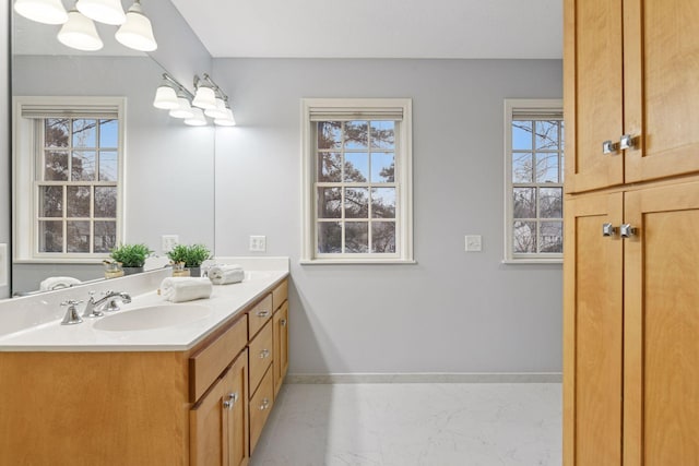 bathroom with double vanity, baseboards, and a sink