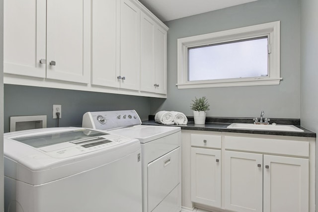 clothes washing area with washing machine and dryer, cabinet space, and a sink