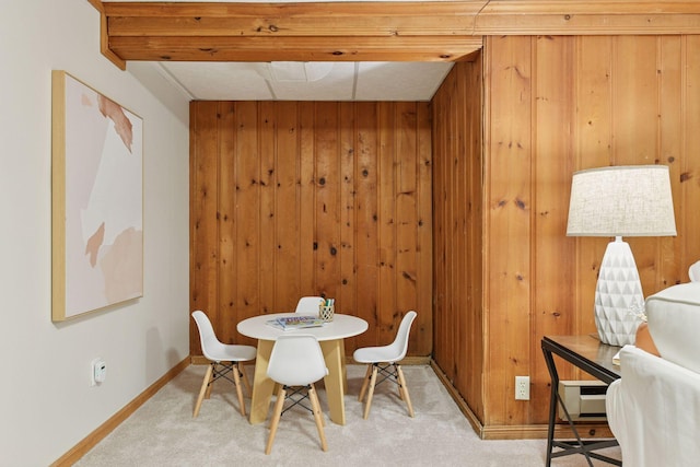 dining area featuring wooden walls, carpet flooring, and baseboards