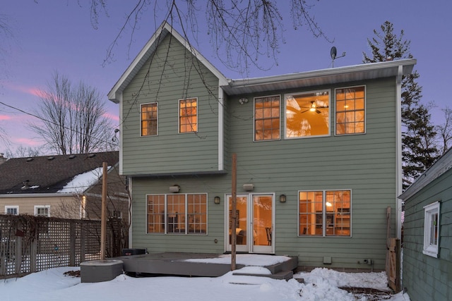 snow covered house featuring fence and a wooden deck