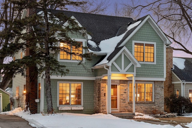 view of front of property featuring stone siding and roof with shingles