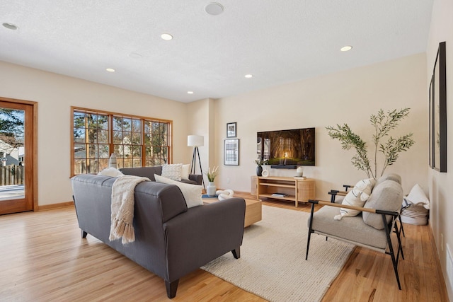 living area featuring light wood-style flooring, recessed lighting, baseboards, and a textured ceiling