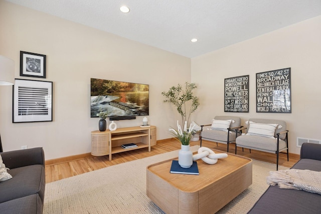 living area with recessed lighting, wood finished floors, visible vents, and baseboards